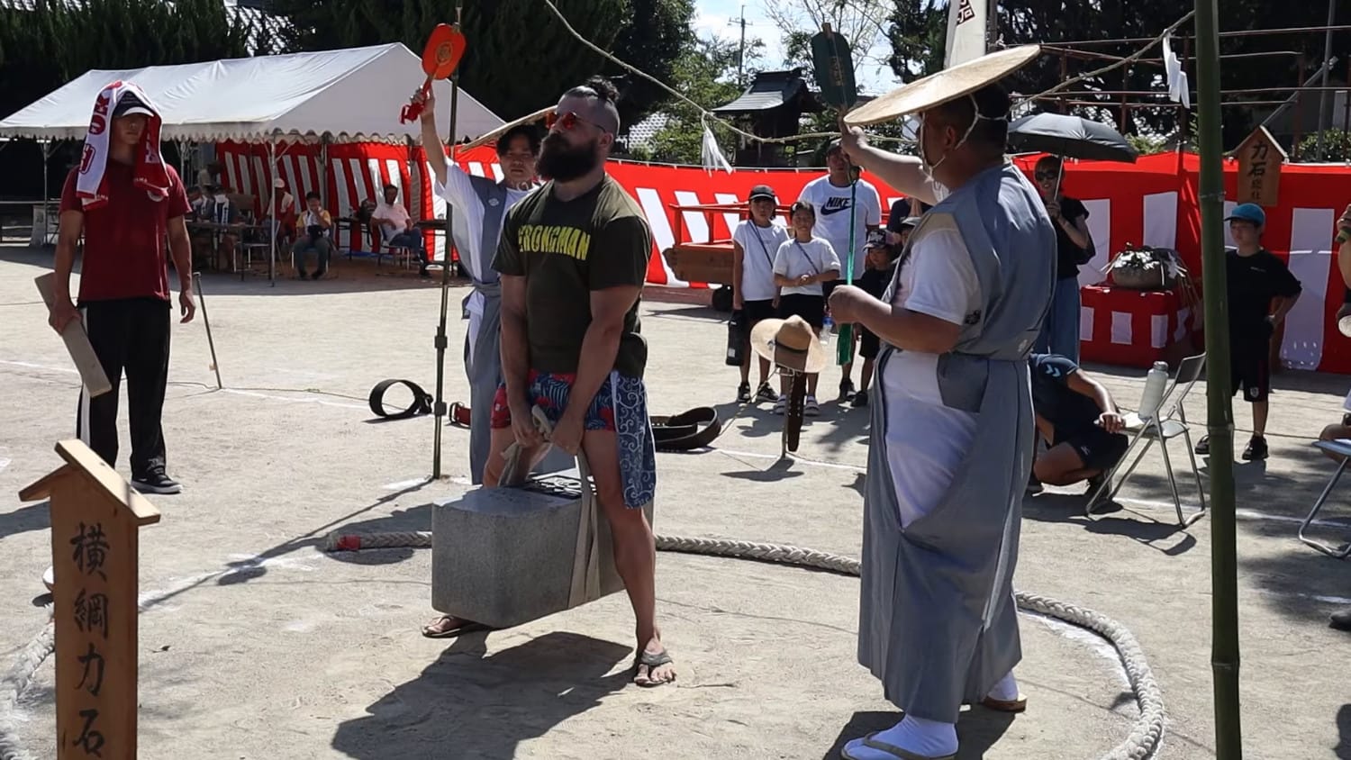 David "Tamotsu" Dunlap stands in a circle holding a heavy block of stone between his legs.