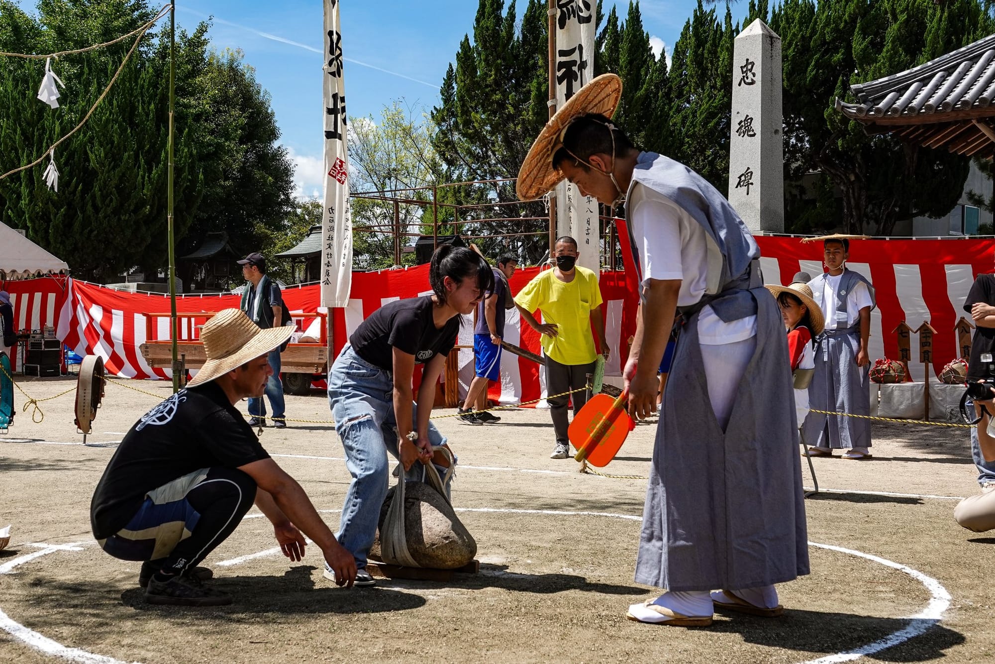 A girl attempts to lift a stone using its harness.