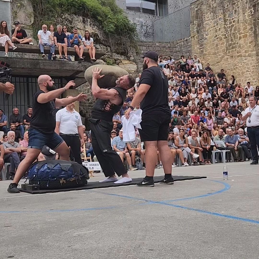 Ryan Steward lifts a large stone to his shoulder while a crowd watches.