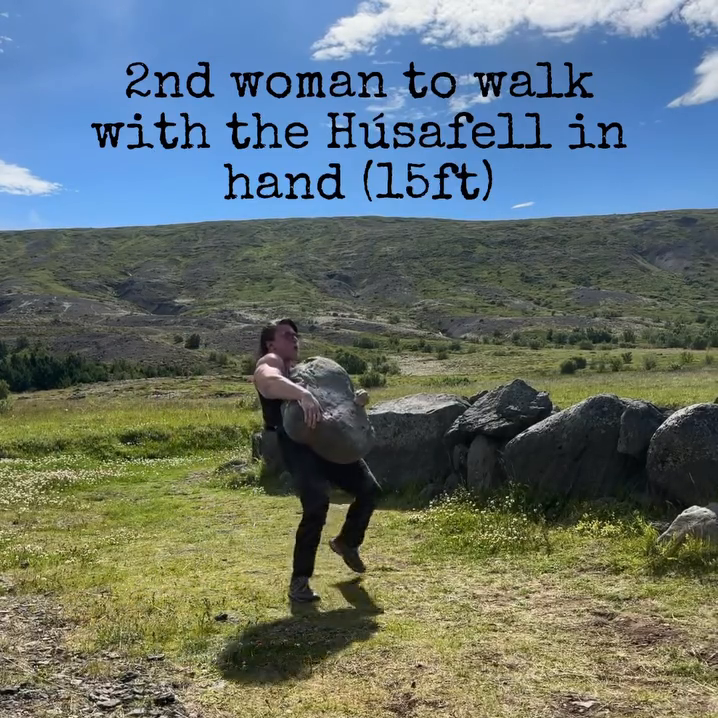 A woman is holding the Húsafell Stone and walking with it.