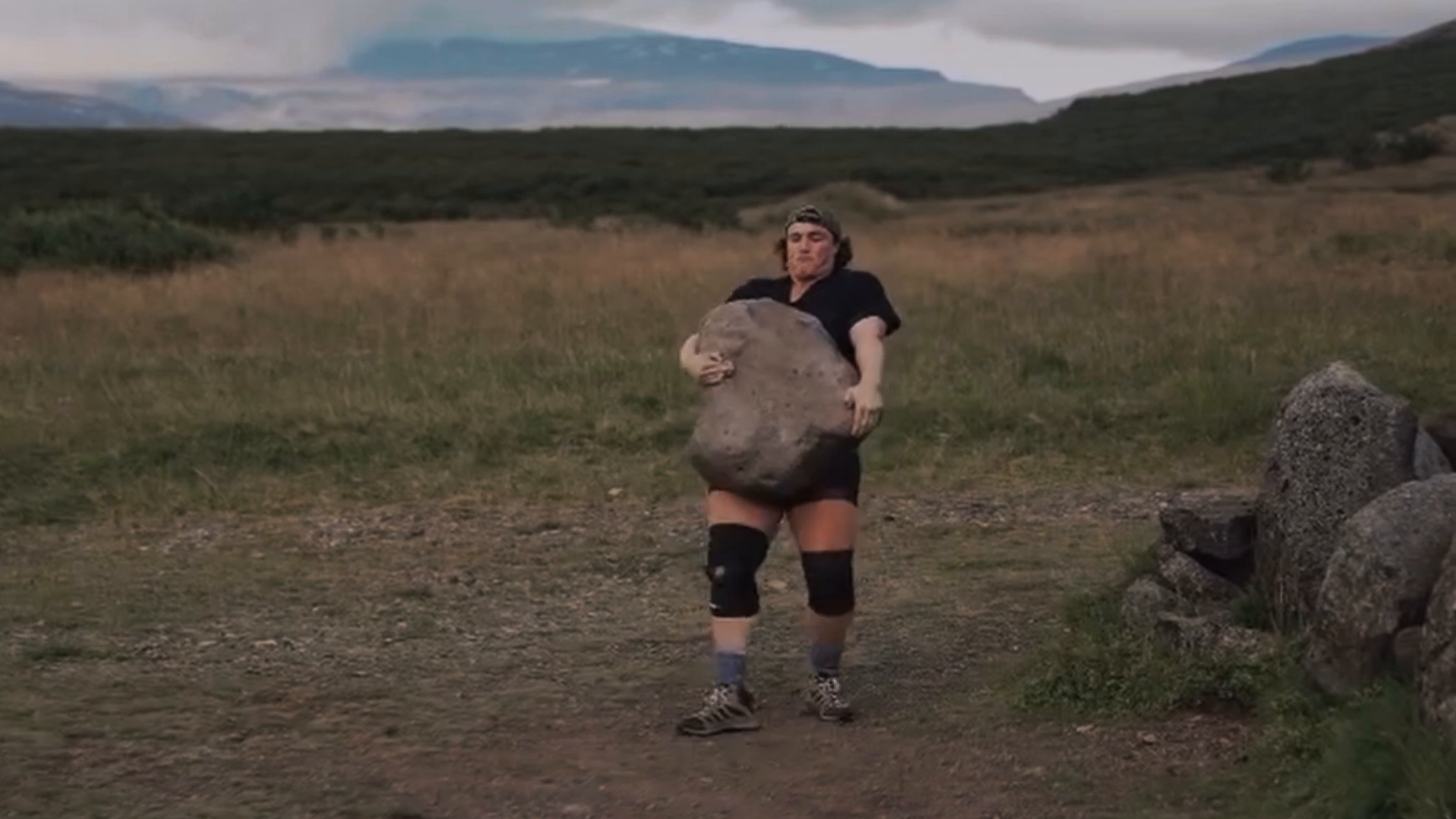 A woman carries the Húsafell Stone.