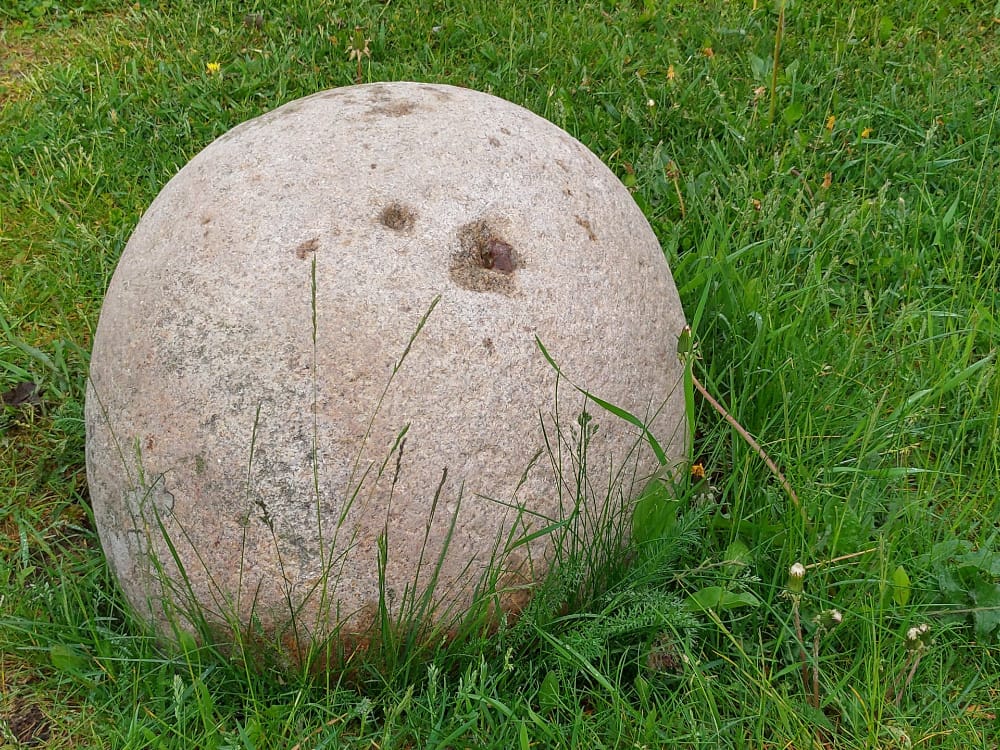 A slightly reddish lifting stone sat on grass.