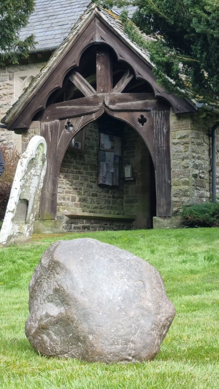 A portrait photograph of the Maegen Stone on the grass in front of the church entrance in Mainstone.