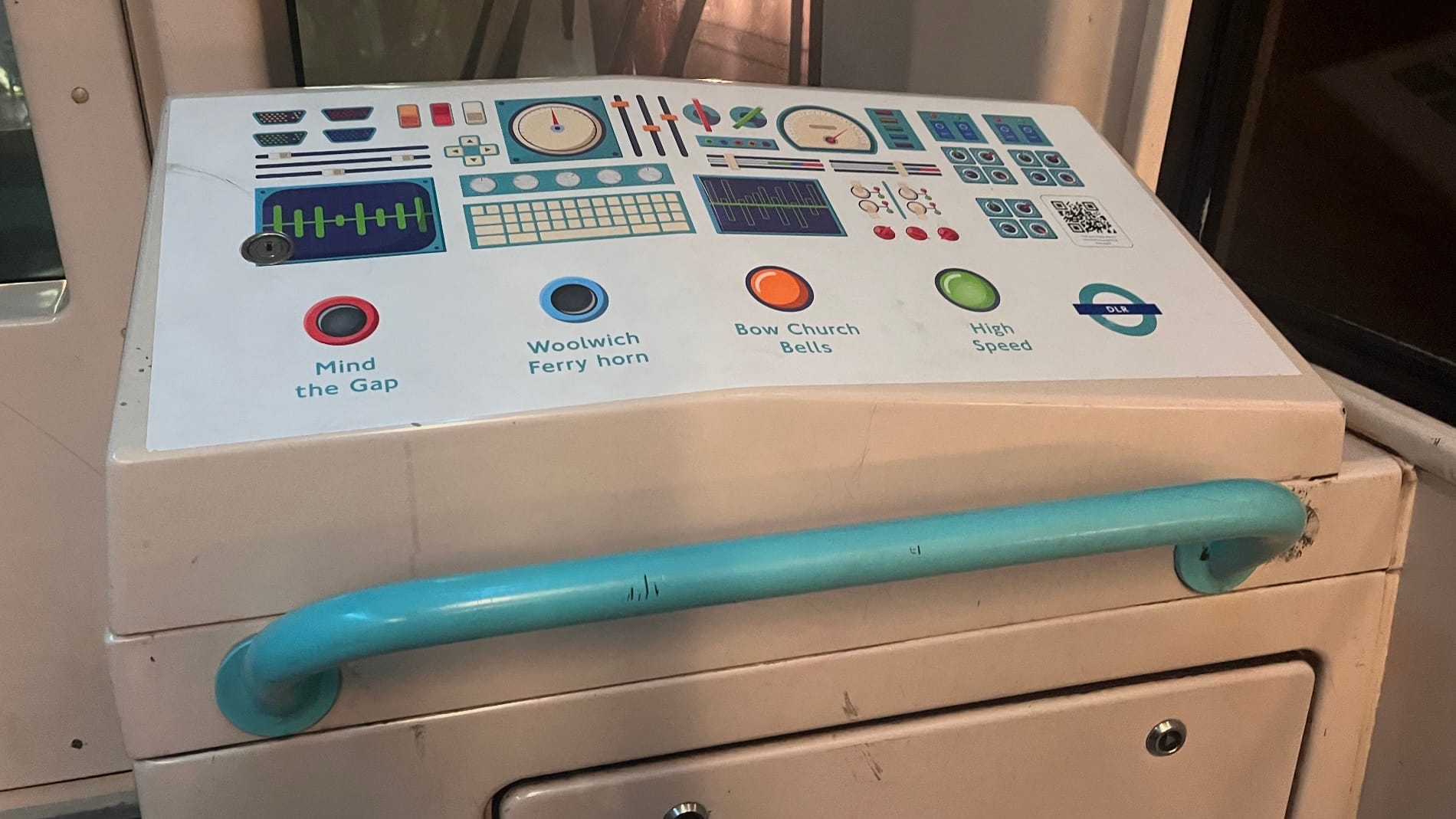 The back of one of the DLR trains, with a handrail and a caricature of the controls of a train.