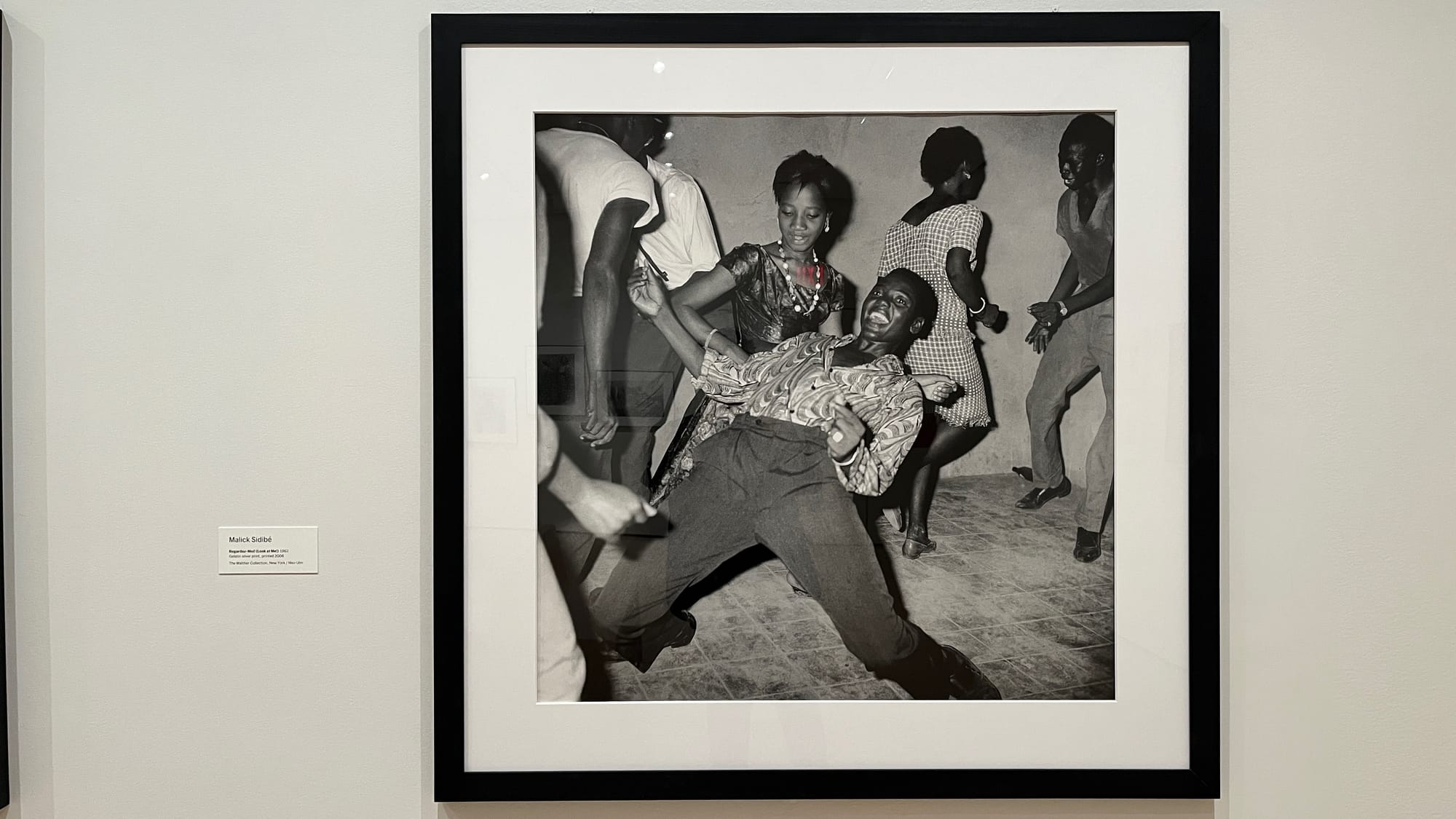 A photography by Malick Sidibé from 1962, titled "Regardez-Moi!" (Look at Me!). It features a bunch of people dancing somewhere in Bamako (probably).