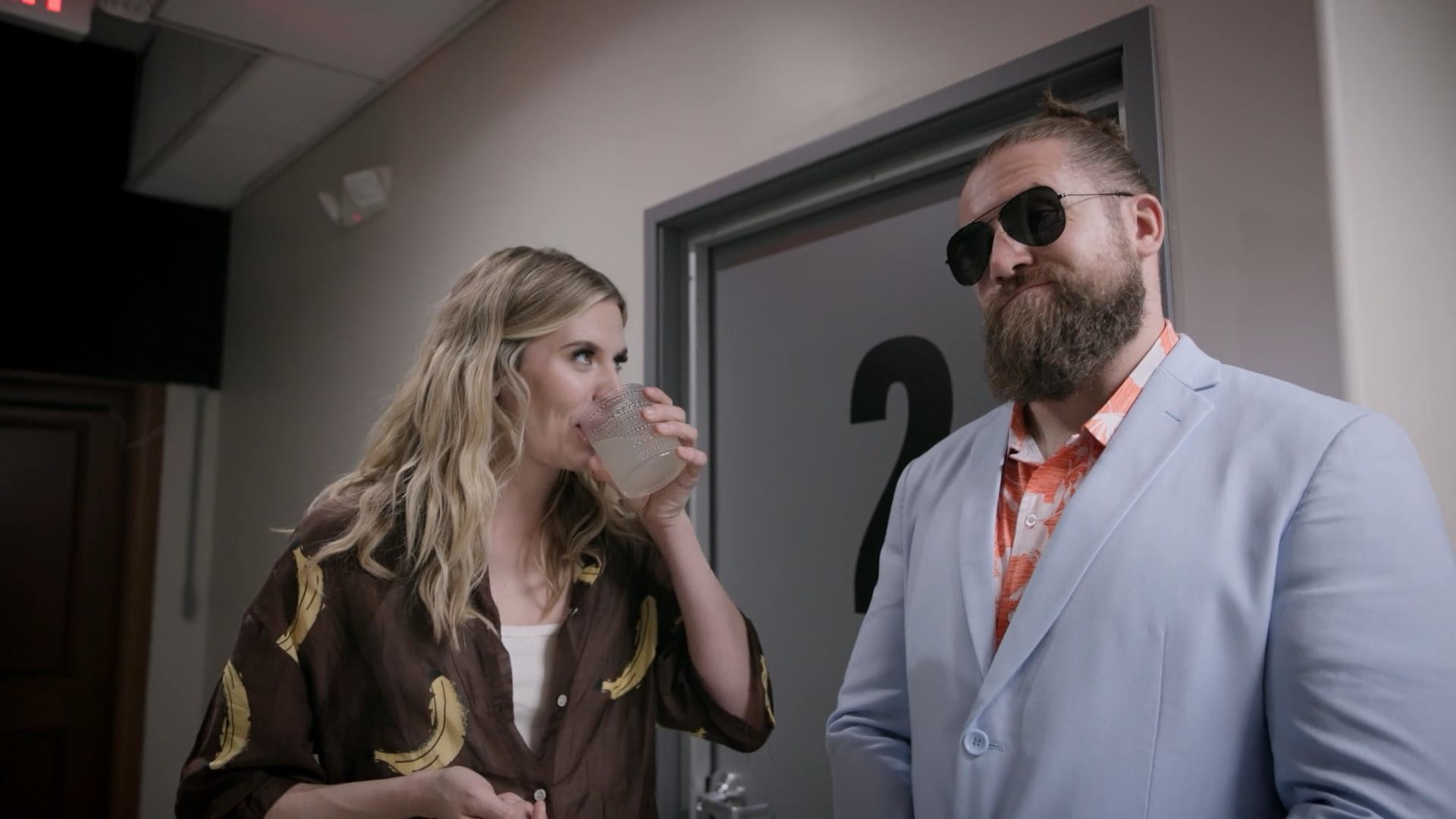 A screenshot from Game Changer S8Ep05, "Count the Rice". Hannah Pilkes is seen flirting with a bouncer with a beard and sunglasses right outside Door 2.
