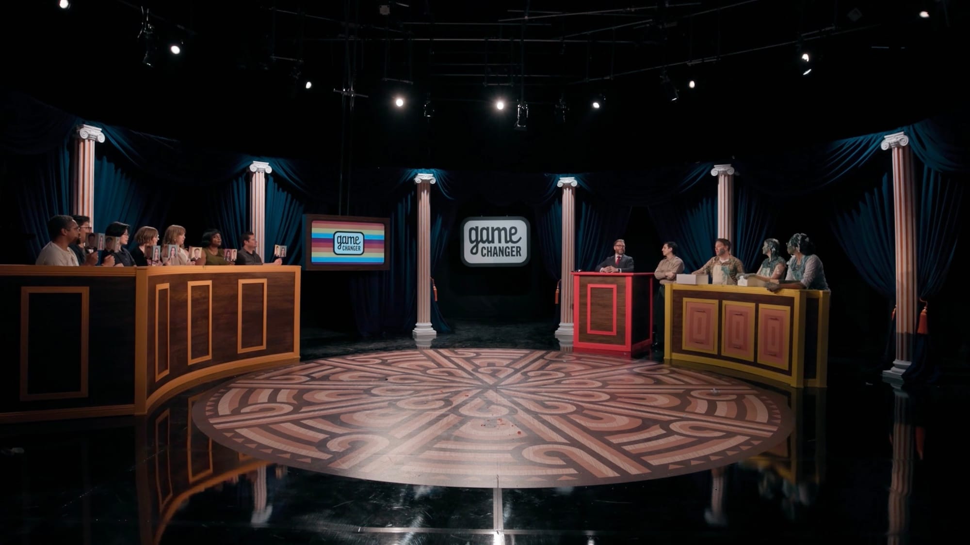 A screenshot from Game Changer S8Ep04, "Kangaroo Court", showing the whole new circle set with all the contestants, jury, Sam, and Paul.