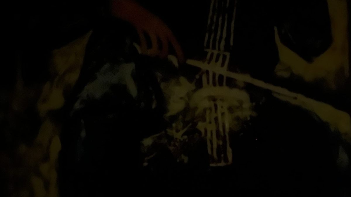 A high-exposure photo of a painting in a dark room. It features multiple splotches of yellow, and small bits of green and red.