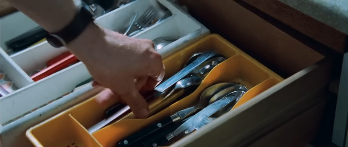 Image from Shaun of the Dead (2004). It features a crash zoom of the main character, Shaun, picking up a knife from a drawer.