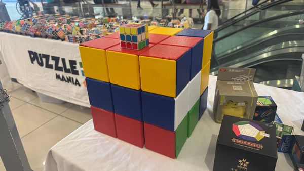 A very large 3D-printed Rubik's Cube. A regular Rubik's Cube with a matching scramble is placed on top, about a fifth the size.