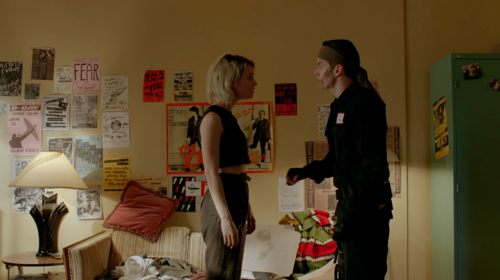 A woman and a man in a spy costume stand in opposition to each other in a home office.