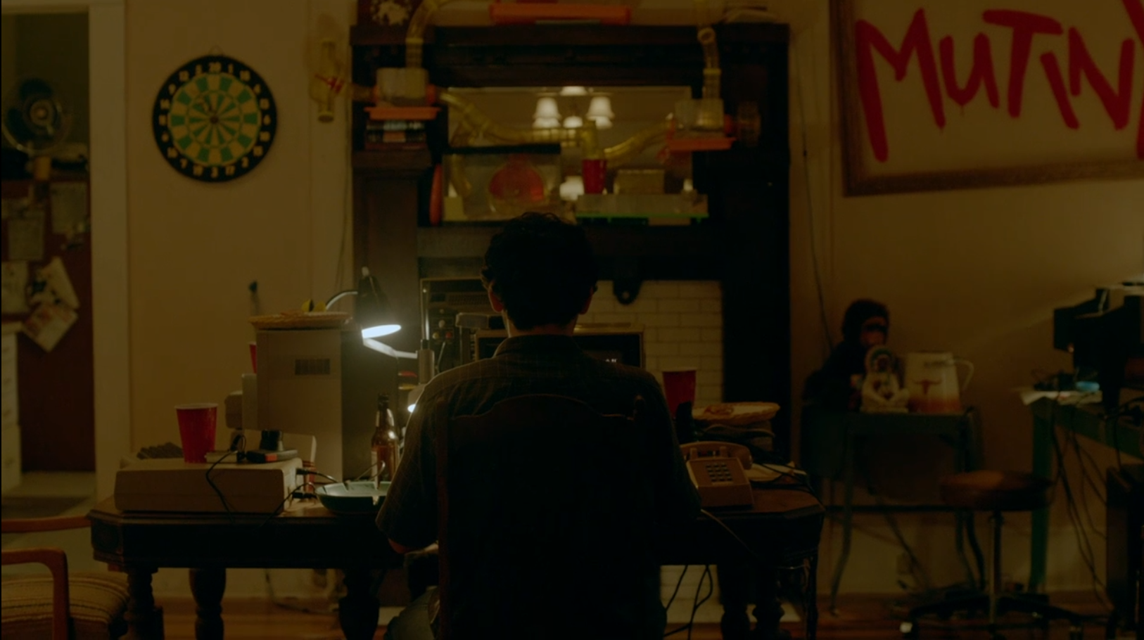 A man sits at his computer in the center of the shot. Something bad and/or confusing just happened on his screen.
