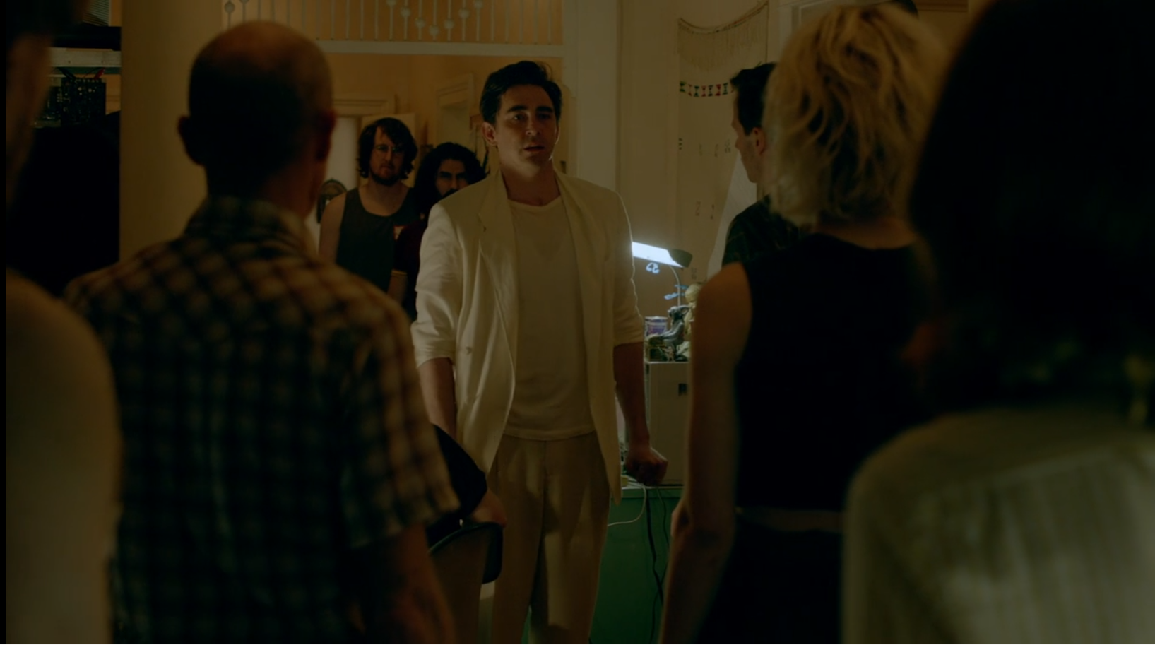A sweaty man in a white suit tries to convince an angry crowd of his innocence.