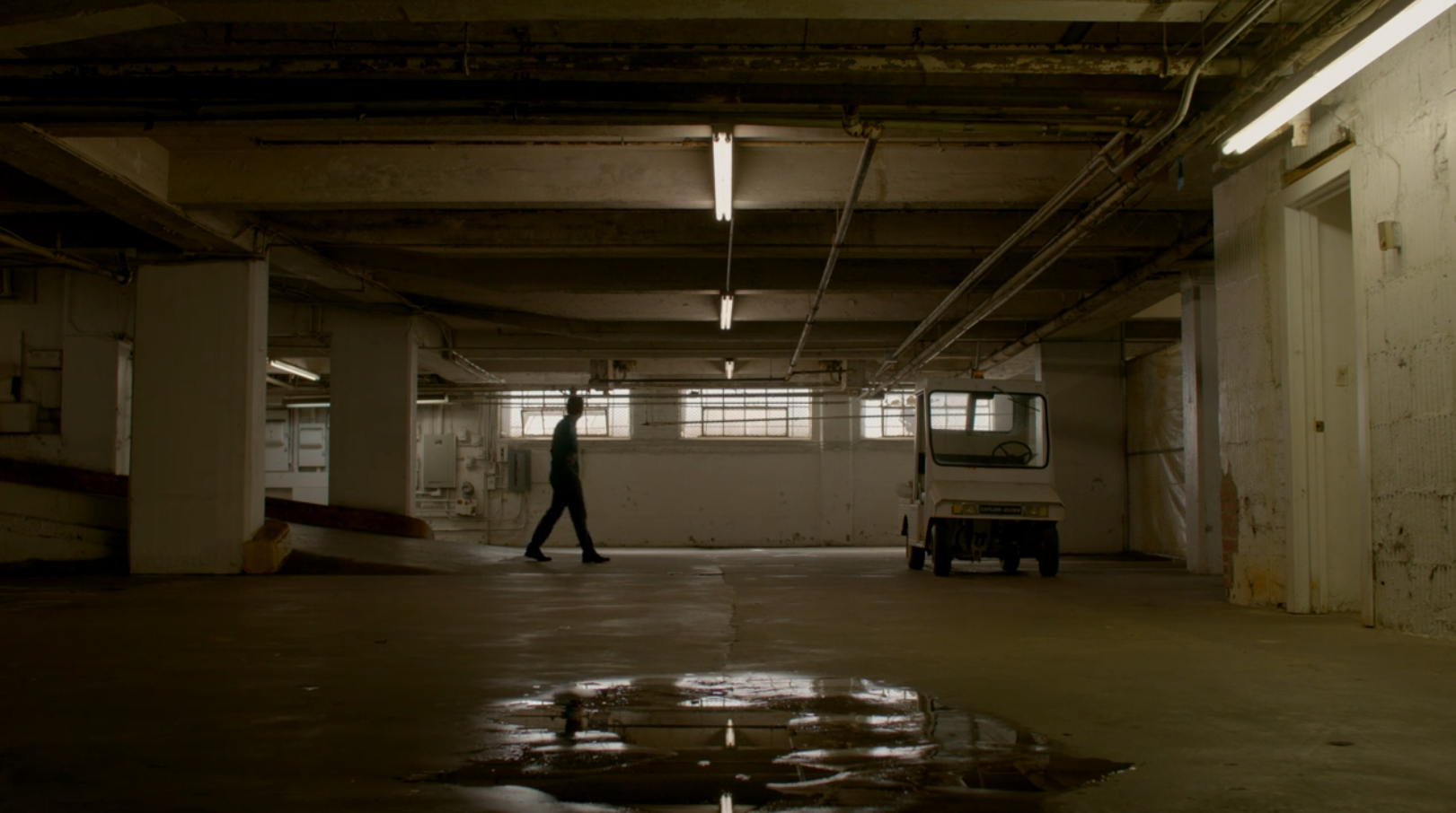 A man wanders alone in the basement of an old parking garage.