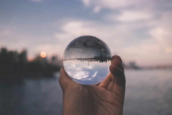 Crystal ball in hand reflecting cityscape, symbolising clarity, perspective, and focused vision