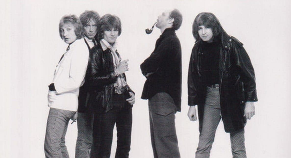 Black-and-white full-length portrait of British Lions circa 1978—Dale Griffin, John Fiddler, Ray Majors, Morgan Fisher, and Overend Watts lined up against a white backdrop.