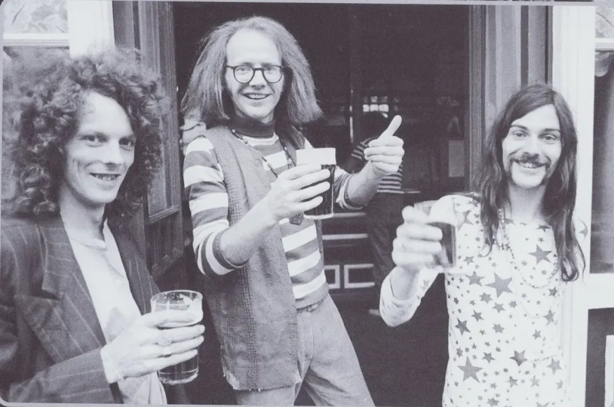 Dr. Strangely Strange raising glasses outside a pub.