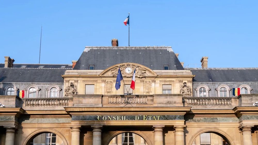 Façade du Conseil d'État à Paris, avec les drapeaux français et européen, symbole de l'administration et des politiques publiques.
