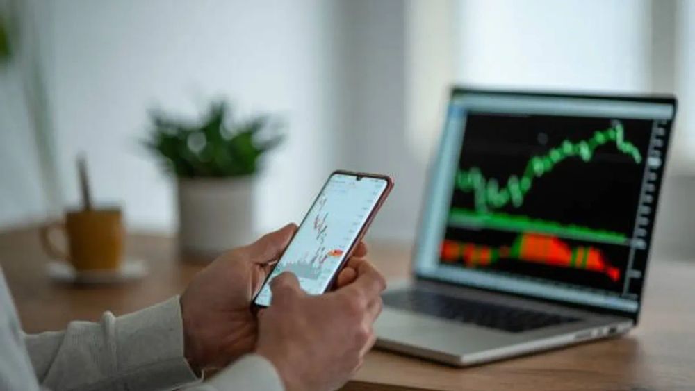 Un trader débutant analyse les graphiques boursiers sur son téléphone et son ordinateur portable.