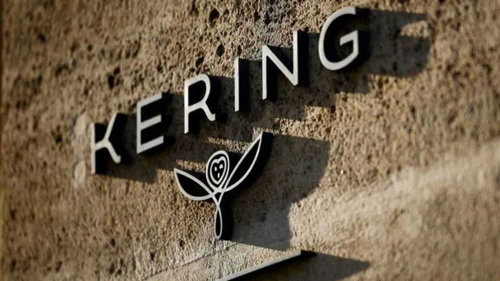 Logo de Kering sur un mur texturé, avec le nom de l'entreprise et un symbole distinctif.
