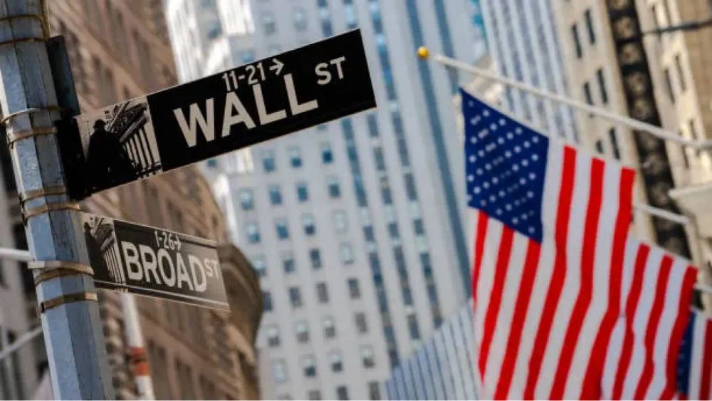 Panneau de signalisation Wall Street et Broad Street avec des drapeaux américains en arrière-plan.