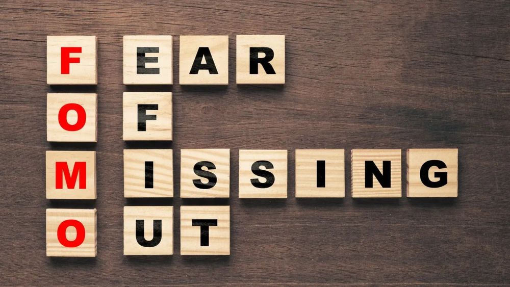 Le mot FOMO (Fear Of Missing Out) écrit avec des cubes en bois sur une table en bois.