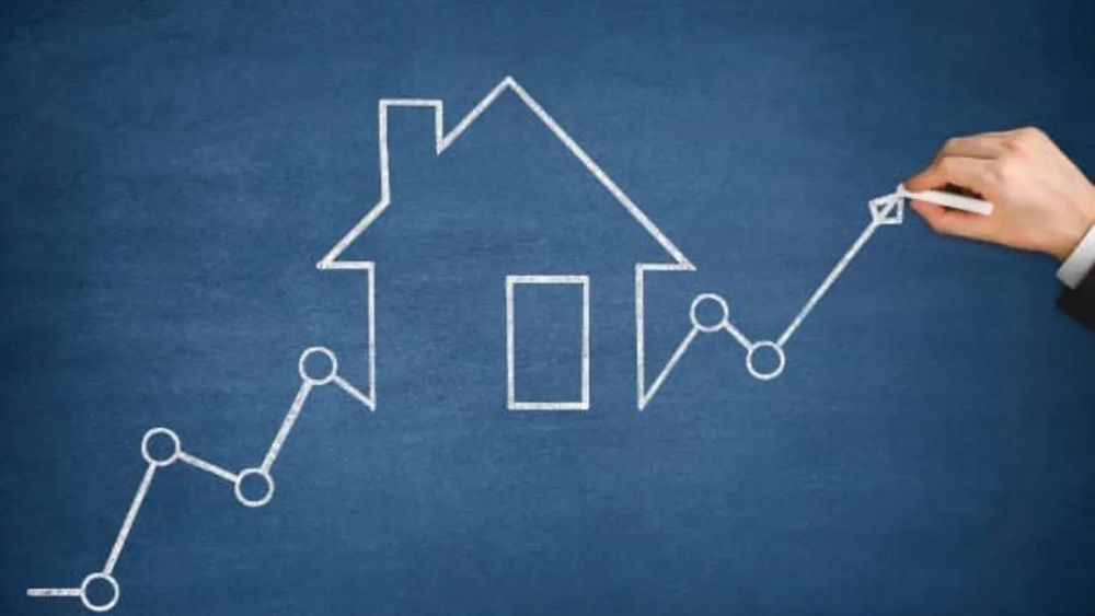 Graphique de l'augmentation des prix de l'immobilier dessiné à la craie sur un tableau bleu, avec une maison au centre.