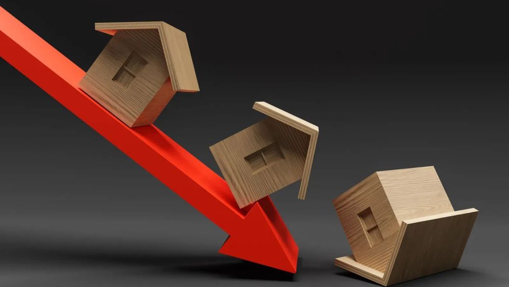 Illustration de la baisse du marché immobilier avec une flèche rouge pointant vers le bas et des maisons en bois qui tombent.