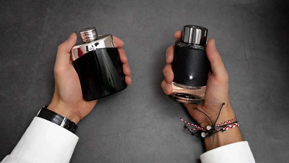 Deux flacons de parfum Montblanc Legend, un noir brillant et un noir texturé, tenus par des mains avec une montre et des bracelets.