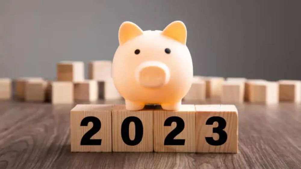 Tirelire cochon sur des cubes en bois affichant l'année 2023, symbolisant l'épargne et les finances pour l'année à venir.
