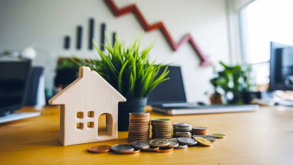 Baisse des prix de l'immobilier : une maison en bois et des pièces symbolisent la crise du marché immobilier français.