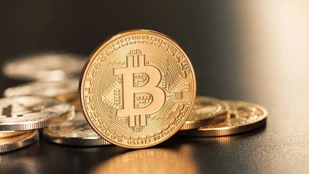 Une pièce de Bitcoin dorée se dresse fièrement parmi d'autres pièces, symbolisant la richesse et l'innovation de la cryptomonnaie.