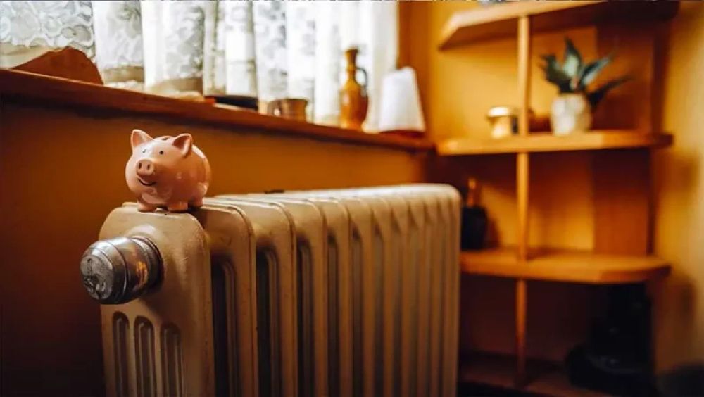 Un cochon tirelire rose posé sur un radiateur, symbolisant les économies d'énergie potentielles grâce à des travaux de rénovation.