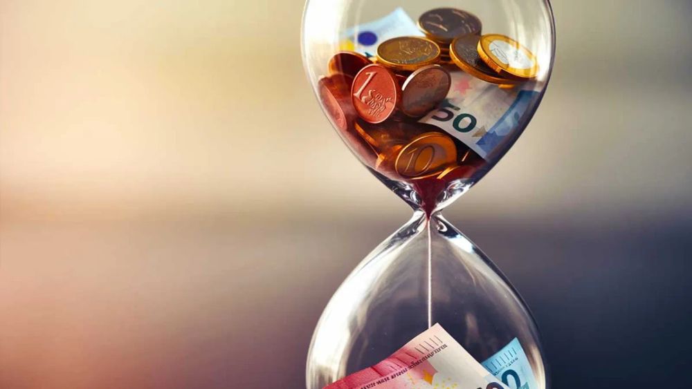Sablier rempli de pièces et de billets en euros, symbolisant l'argent qui s'écoule et se perd avec le temps.