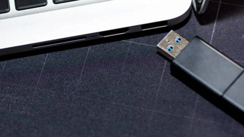 Clé USB à côté d'un ordinateur portable, symbolisant le stockage sécurisé des clés privées d'un wallet crypto.