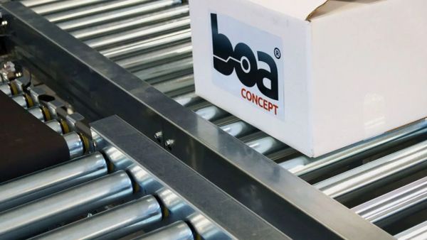 Un carton avec le logo BOA Concept sur un convoyeur à rouleaux, illustrant l'innovation logistique.