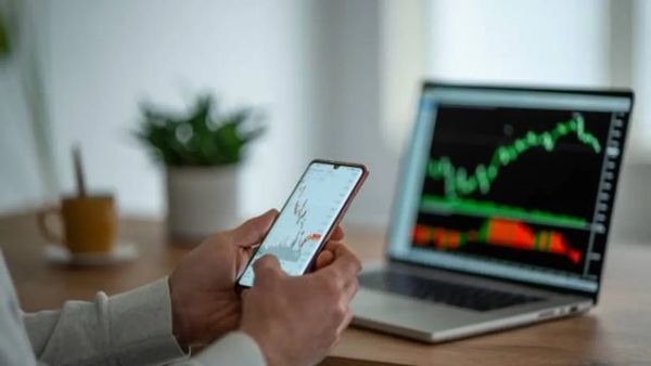 Un trader débutant analyse les graphiques boursiers sur son téléphone et son ordinateur portable.