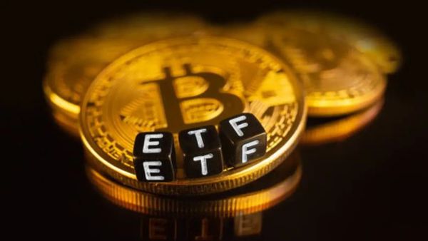Pièces Bitcoin avec des dés noirs épelant ETF, représentant un ETF Bitcoin.