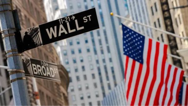 Panneau de signalisation Wall Street et Broad Street avec des drapeaux américains en arrière-plan.
