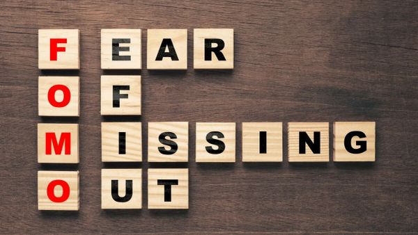 Le mot FOMO (Fear Of Missing Out) écrit avec des cubes en bois sur une table en bois.