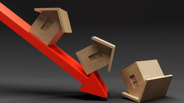 Illustration de la baisse du marché immobilier avec une flèche rouge pointant vers le bas et des maisons en bois qui tombent.