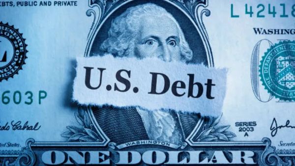 Un billet d'un dollar américain avec les mots "Dette américaine" écrits sur un morceau de papier qui recouvre le visage de George Washington.