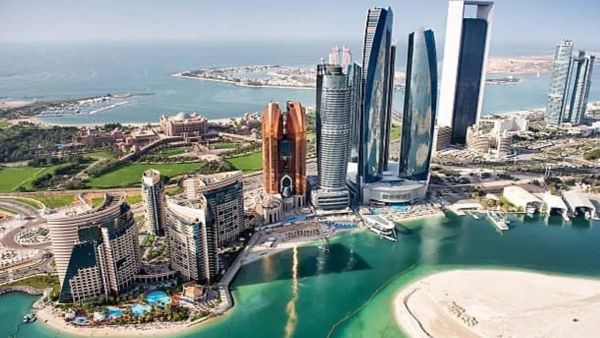 Vue aérienne de la ville d'Abu Dhabi, Émirats arabes unis, avec ses gratte-ciel modernes et ses eaux turquoise, un lieu d'investissement immobilier potentiel.