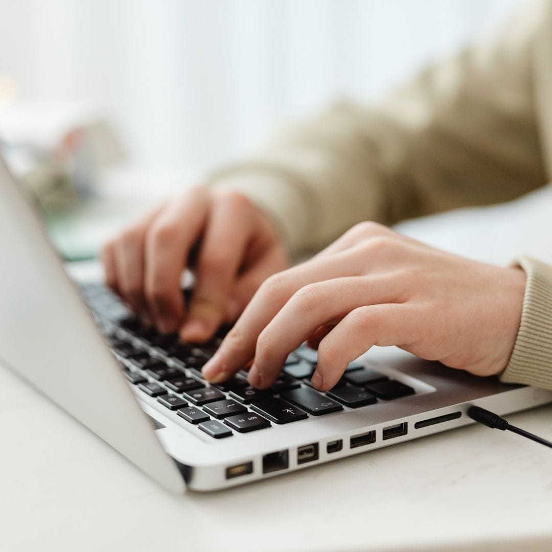 A close up of hands typing on a laptop