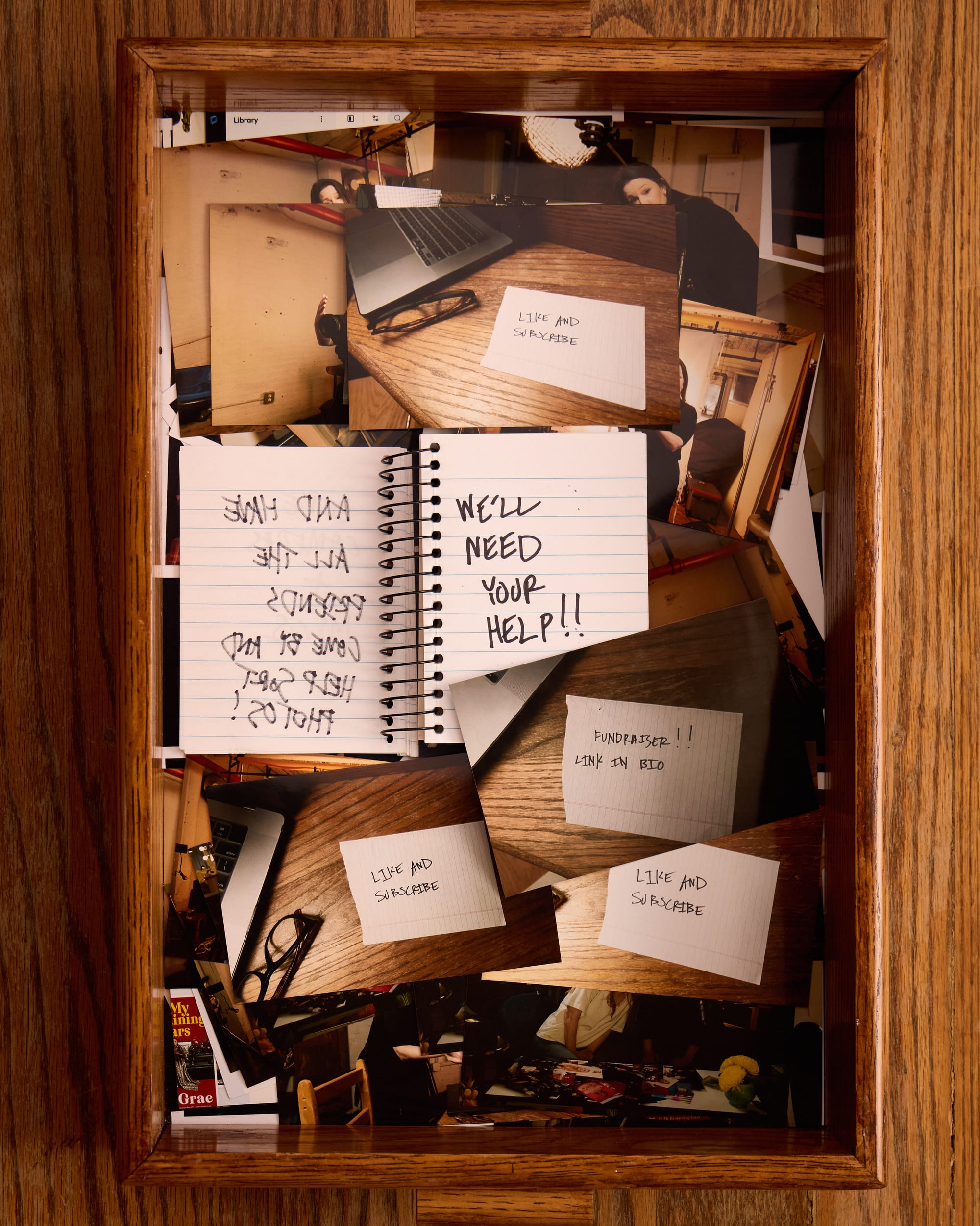 The notebook now says “We'll need your help!” In the tray of 4x6 photos, there are handwritten calls to like and subscribe as well as a note that there’s a fundraiser link. 