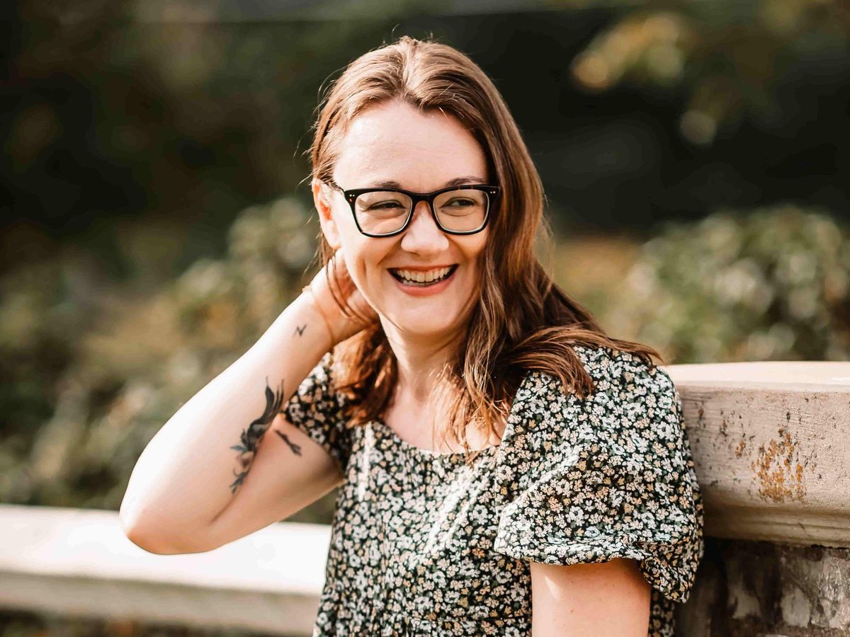 A photo of Anna Burgess Yang wearing a floral dress and glasses