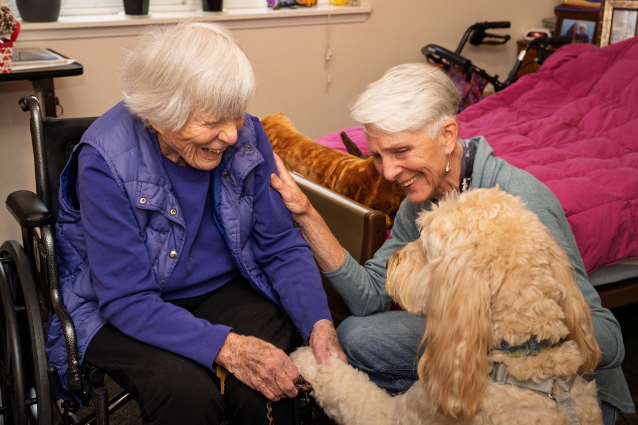   Goldendoodle Jake and owner Keri French enjoy spending time with patient Eva. Photo by Luc Schoonjans.  