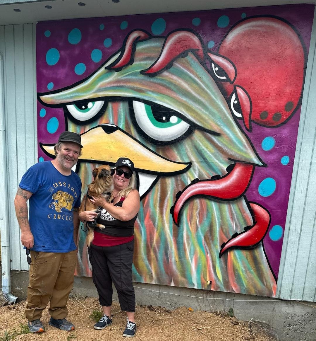   Ryan Henry Ward, the artist known simply as “Henry,” poses with the sasquatch head on Christina Maloney’s office for her business, Hood Canal Adventures. Submitted photo  
