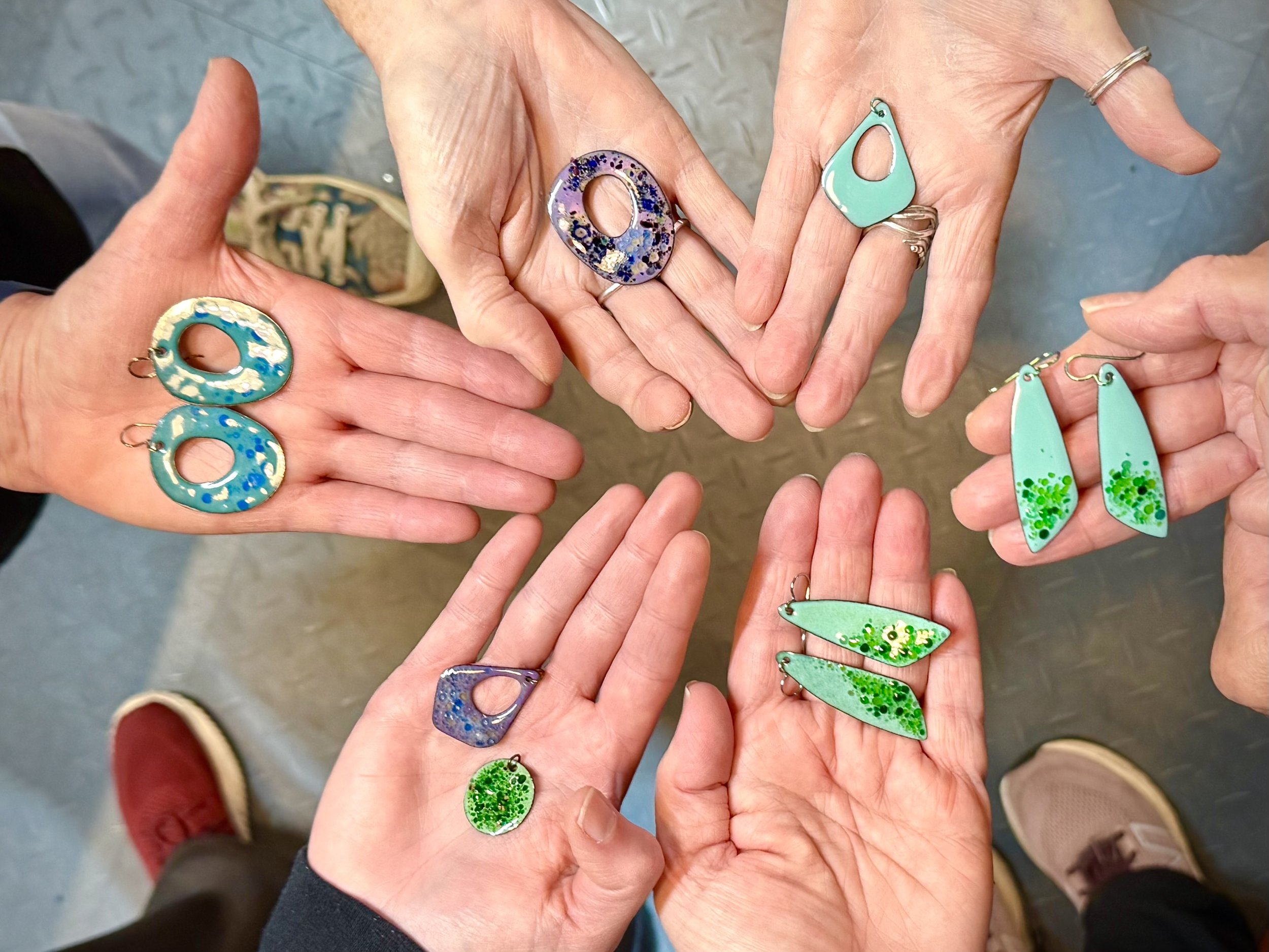   Northwind Art Jewelry Studio students show off the enamel earrings made in a recent Sunday workshop. Photo by Diane Urbani.   