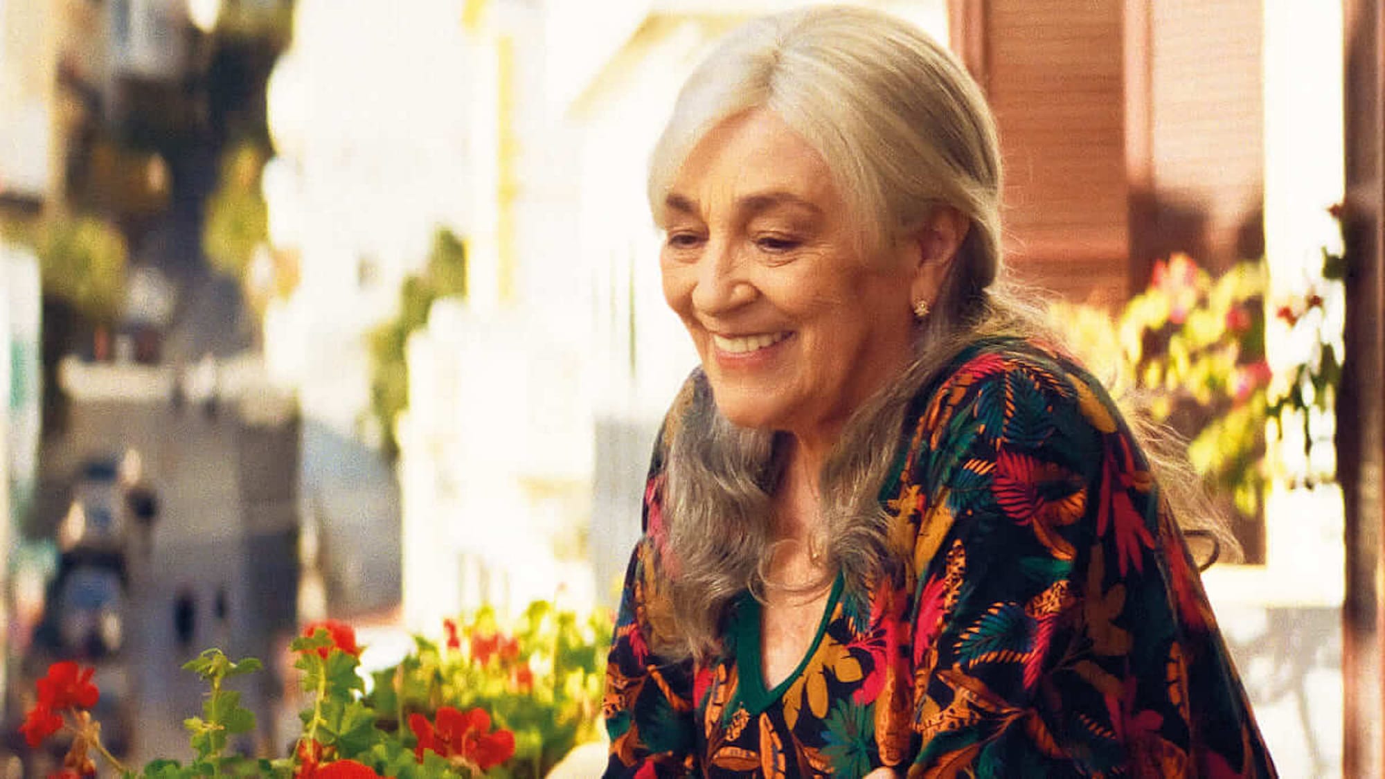 Carmen Maura in front of flowers in flower patterned blouse.&nbsp;
